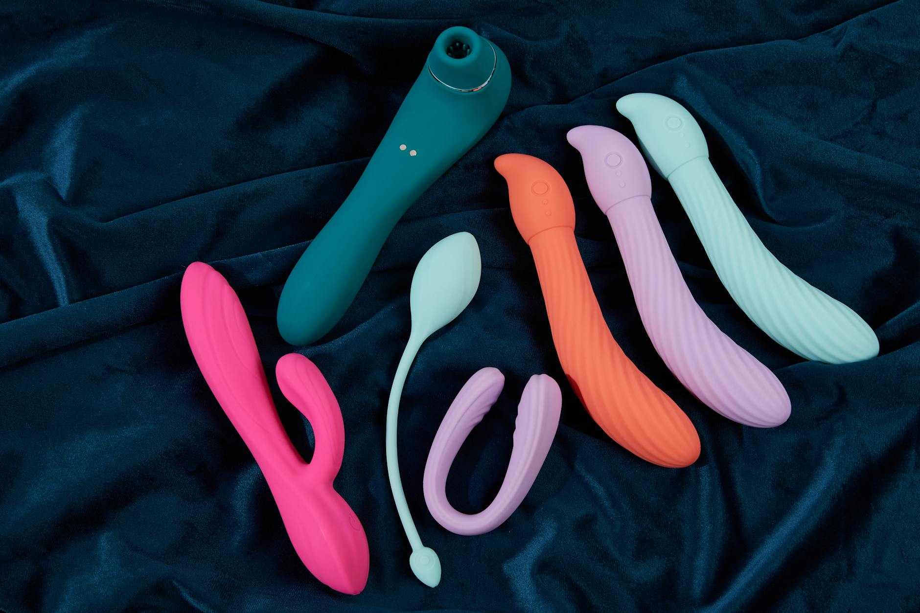 Una mano che tiene un vibratore blu sopra una ciotola decorativa di vetro, mostrando la trama del prodotto