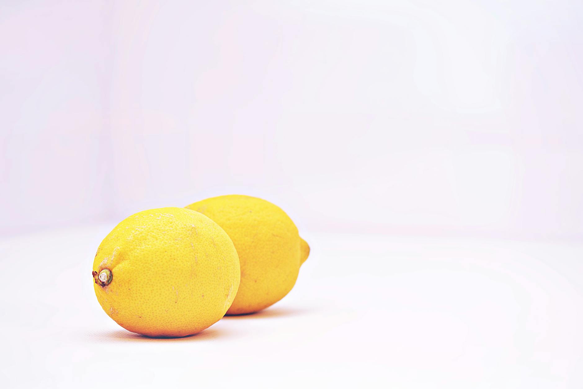Due limoni vibranti su sfondo bianco minimalista che simboleggiano freschezza e sensibilità sessuale