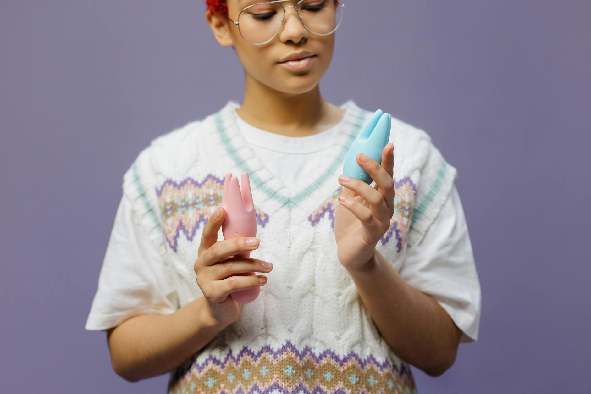 Mani che tengono vibratori in silicone blu e rosa, esplorando nuove sensazioni di piacere