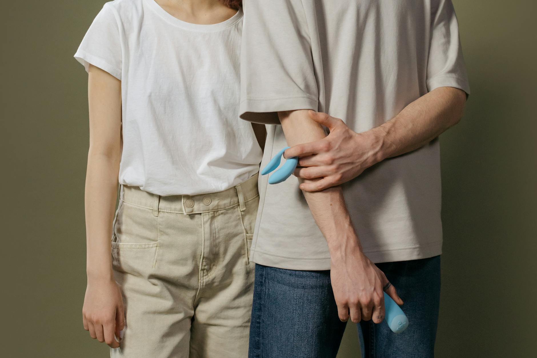 Una mano che tiene un vibratore blu sopra una ciotola decorativa di vetro